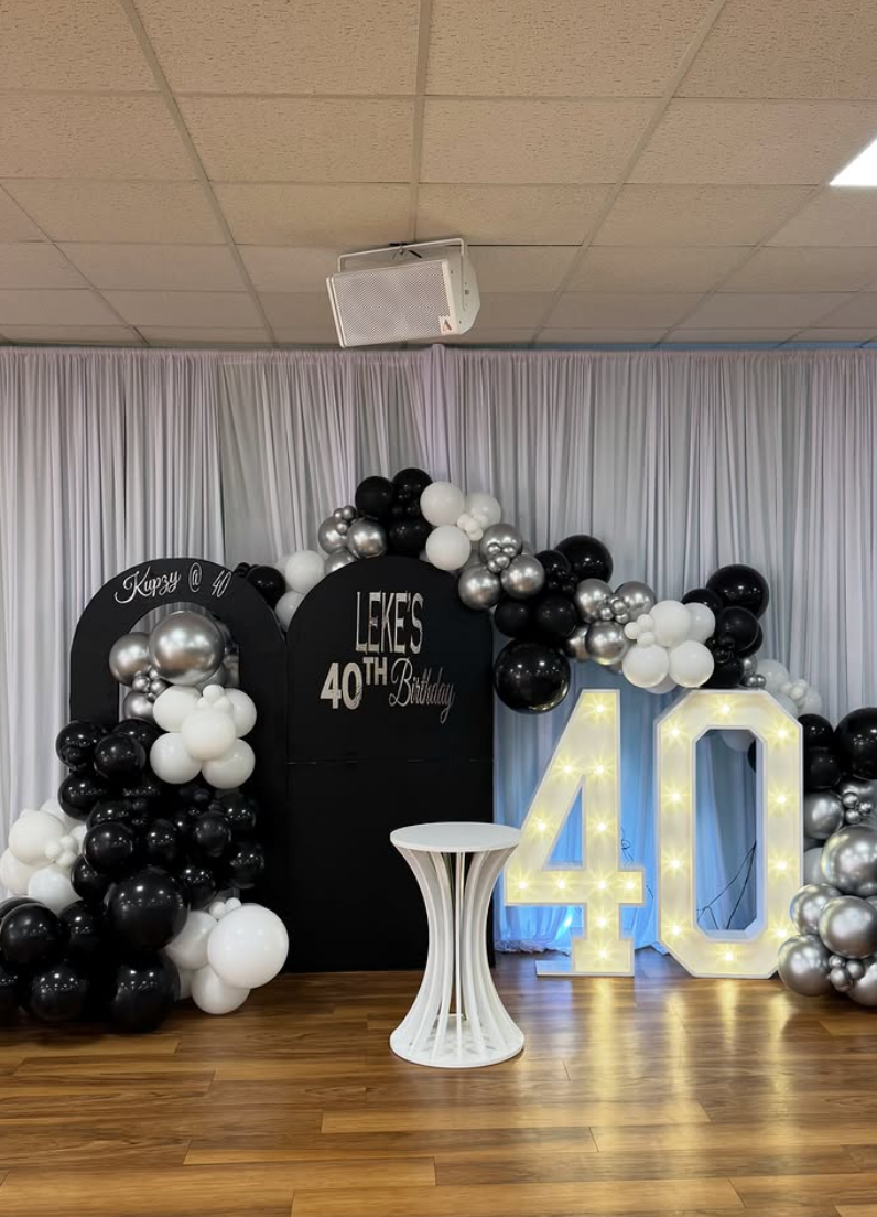 Draped backdrop with a black and silver 40th birthday balloon arch and light-up marquee numbers