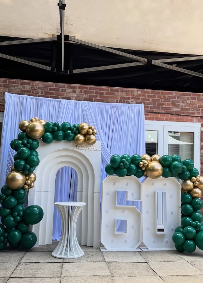 Green and gold balloon garland with light-up 60 numbers and draped backdrop by Ta Luxe Events
