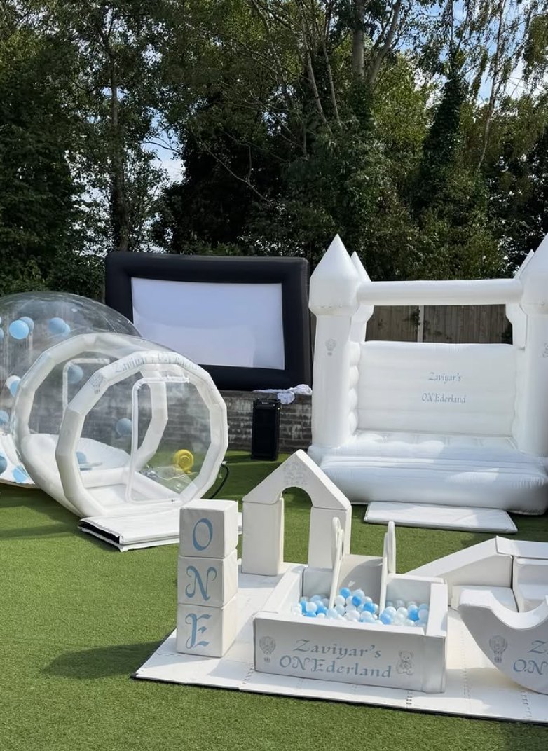 White bouncy castle and clear bubble dome set up in a garden with soft play blocks